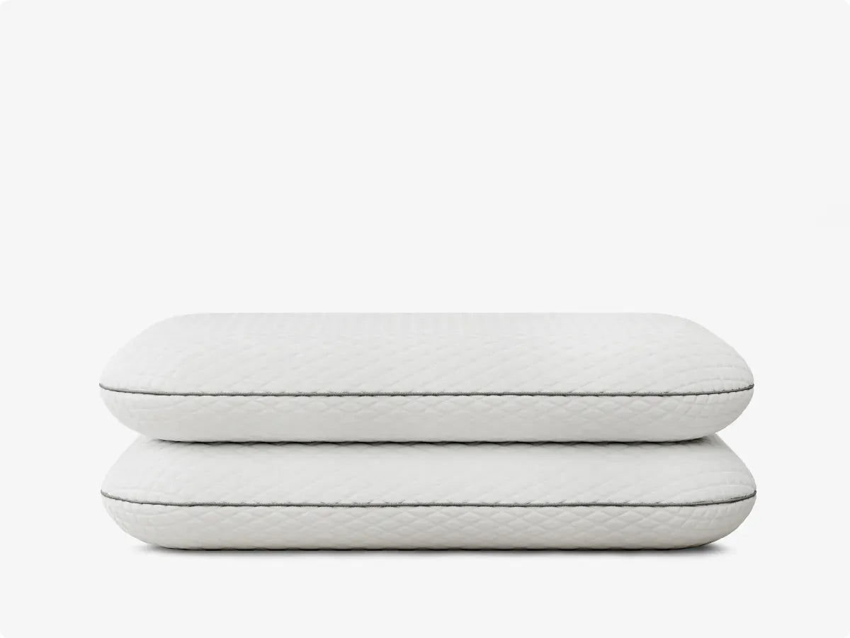 Two white quilted pillows stacked on a white background
