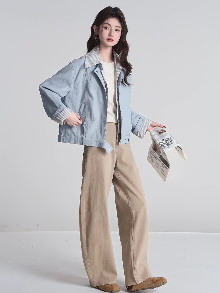 Full body shot of a woman in a light blue bomber jacket and tan pants