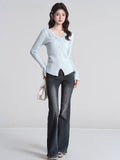 Full body shot of a woman in a light blue ribbed knit cardigan and dark wash jeans
