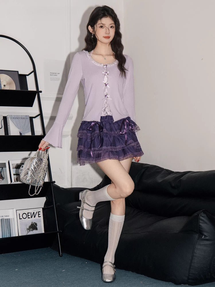 Woman posing in a light purple long-sleeve knit top, purple tiered lace skirt, knee-high socks, and silver shoes