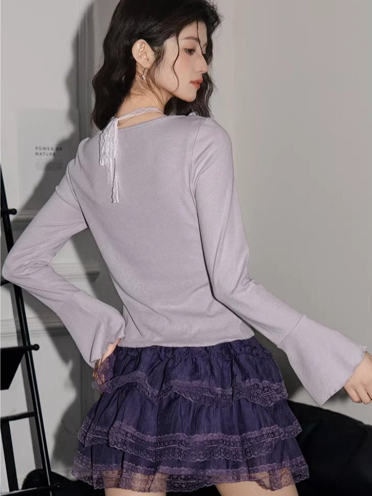 Woman wearing a light purple long-sleeve knit top with ribbon ties and a purple tiered lace skirt
