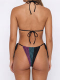 Woman wearing a sparkly triangle bikini with black, purple, and teal panels from the back
