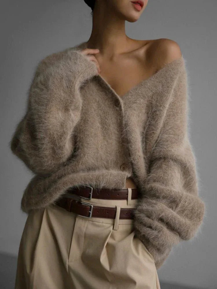 Woman wearing a beige fuzzy knit cardigan with a v-neck and button front closure.