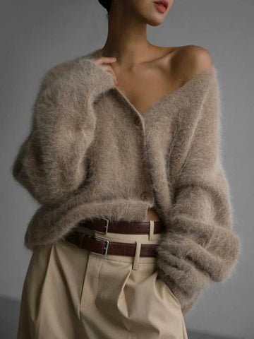 Woman wearing a beige fuzzy knit cardigan with a v-neck and button front closure.