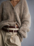 Model wearing a beige fuzzy knit cardigan and beige trousers with a brown belt.