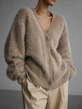 Close-up of a beige fuzzy knit cardigan on a model.