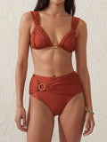 Woman wearing a rust-colored ruched bikini top with gold ring detail