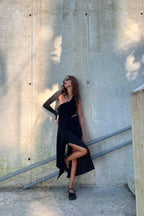 Model wearing a black asymmetrical one-sleeve gown outdoors