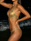 Woman wearing a gold metallic halter bikini top and bottoms from the side