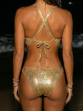 Woman wearing a gold metallic halter bikini top with criss-cross back straps and bottoms from the back