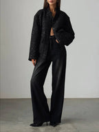 Full body shot of a woman in a black sequined textured cropped jacket and dark wash wide-leg jeans.
