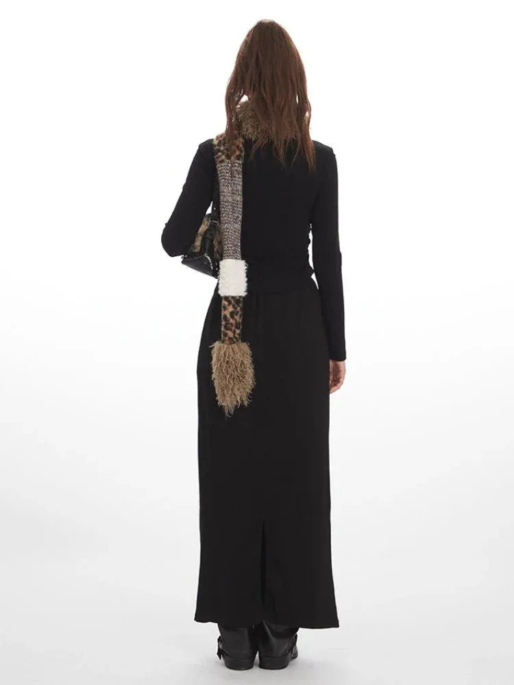 Woman wearing a black long-sleeve top and a black maxi skirt with star graphics, accessorized with a patterned scarf