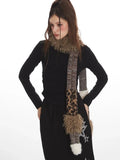 Close-up of a woman wearing a black long-sleeve top and black maxi skirt with star graphics and a patterned scarf