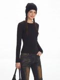 Woman posing in a black fitted knit top and denim.