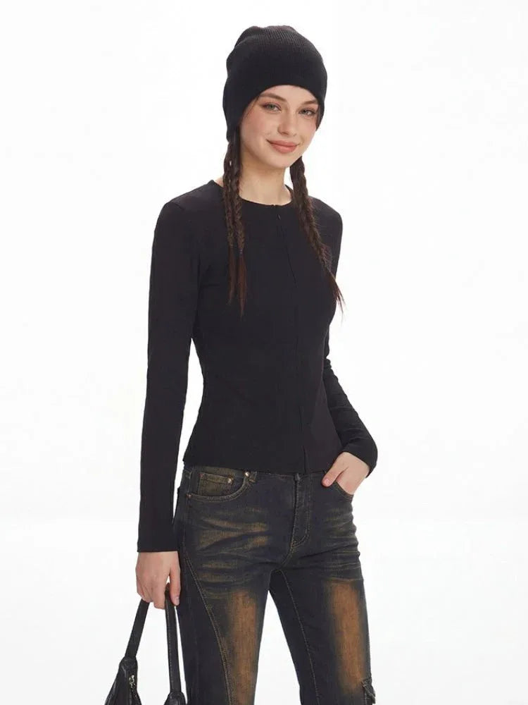 Woman posing in a black fitted knit top and denim.