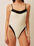 Woman wearing a cream and black one-piece swimsuit from the front