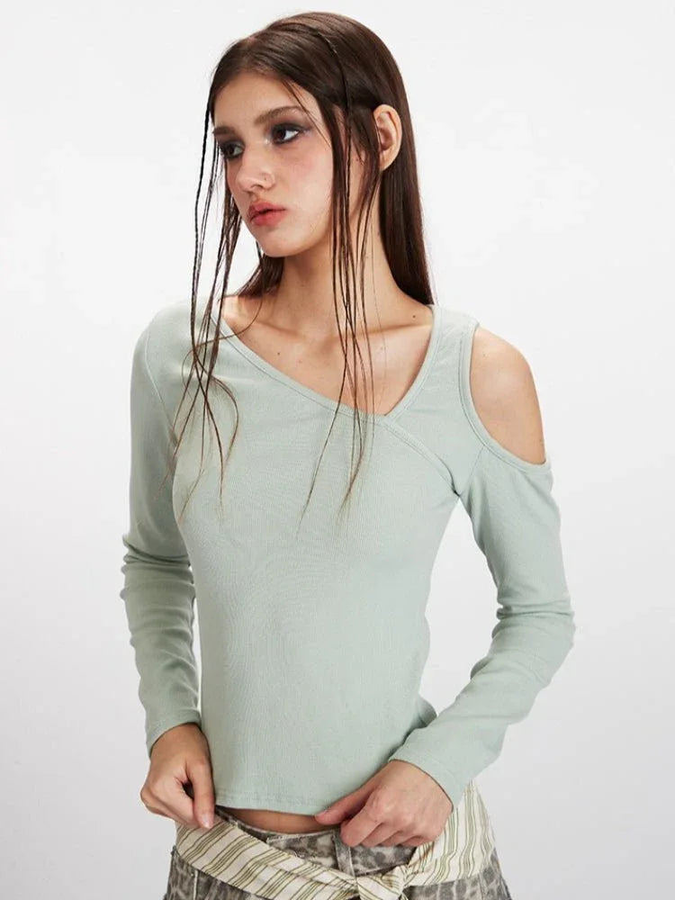 Front view detail of a light green long-sleeve ribbed knit top with asymmetrical neckline and cold shoulder cutouts.