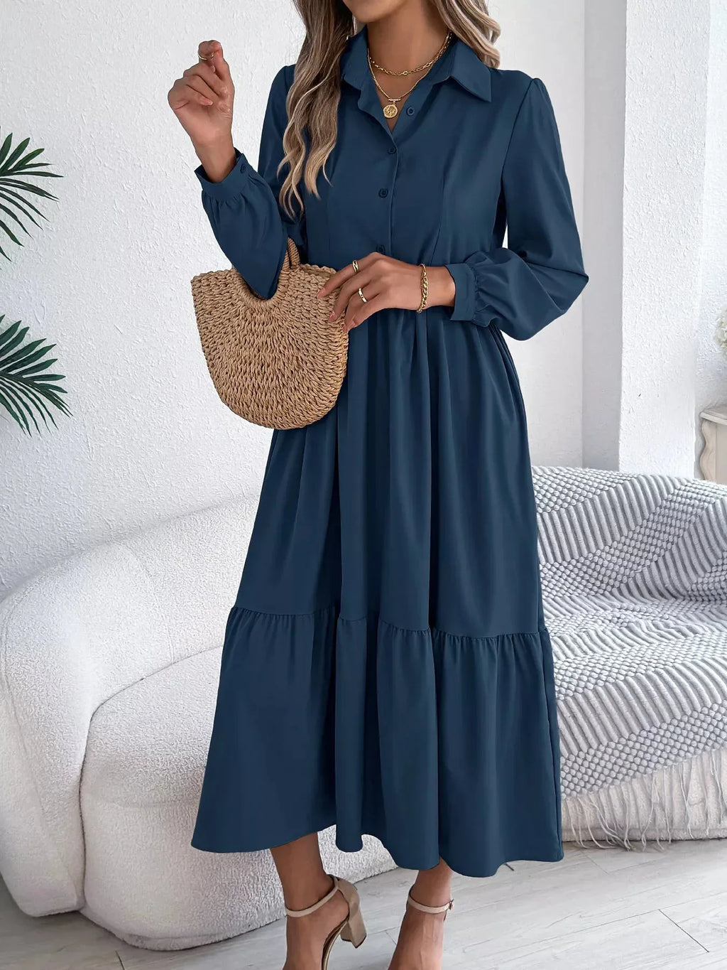 Close-up of a woman's hands holding a straw bag while wearing a navy blue midi dress.