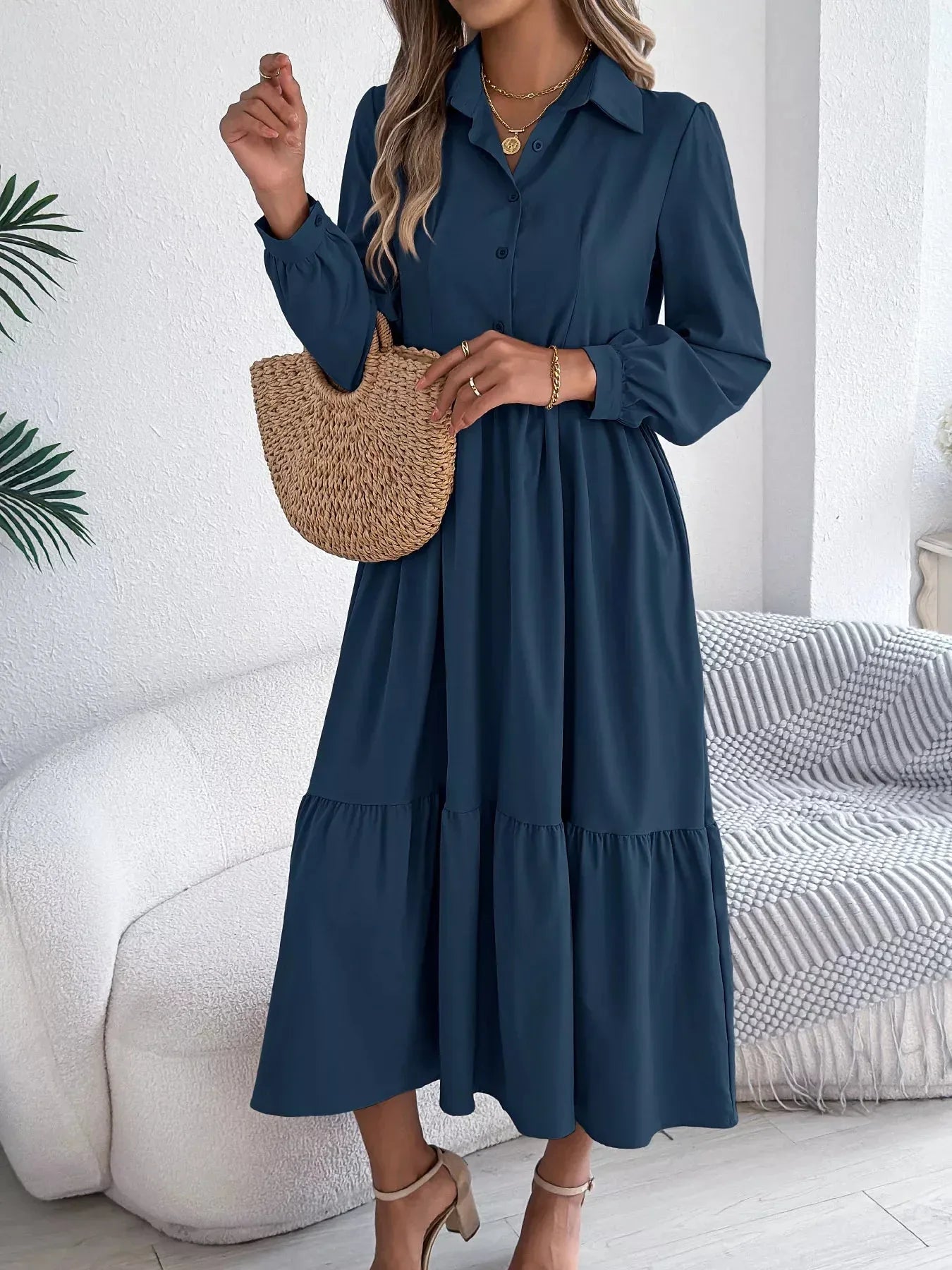 Close-up of a woman's hands holding a straw bag while wearing a navy blue midi dress.