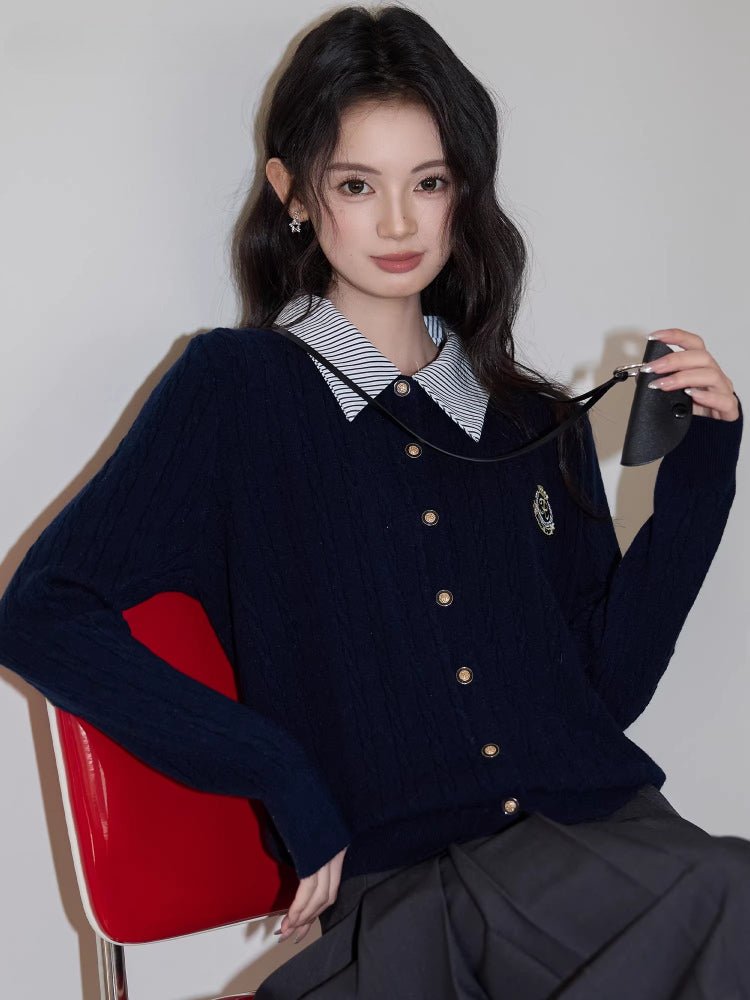 Woman wearing a navy blue cable knit cardigan with a striped collar and embroidered emblem