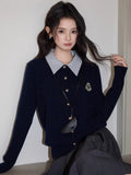 Woman seated in a chair wearing a navy blue cable knit cardigan and a dark skirt