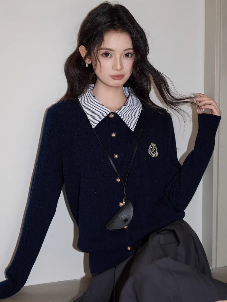 Woman seated in a chair wearing a navy blue cable knit cardigan and a dark skirt