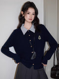 Woman posing with a navy blue cable knit cardigan layered over a striped shirt