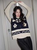 Woman wearing a navy and cream knit zip-up vest with floral pattern