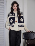 Woman posing in a navy and cream knit zip-up vest over a cream turtleneck