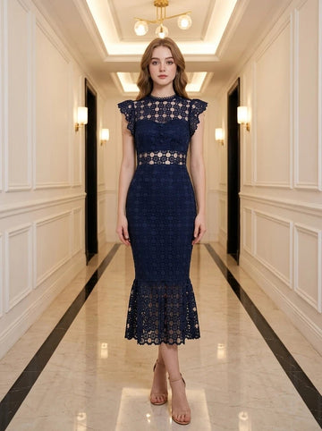 Woman in a navy blue lace midi dress with a high neckline and ruffled cap sleeves, standing in a hallway.