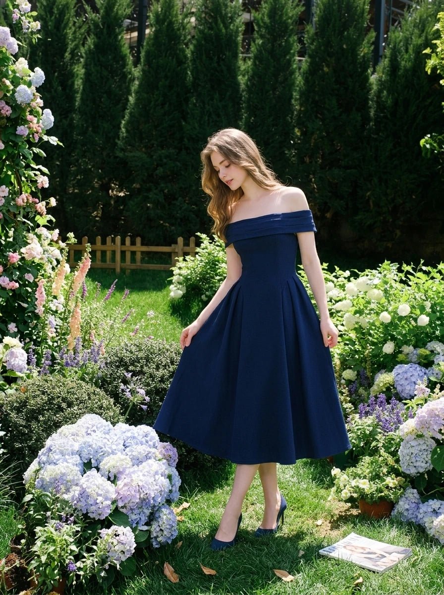 Woman in a navy blue off-the-shoulder dress standing in a garden