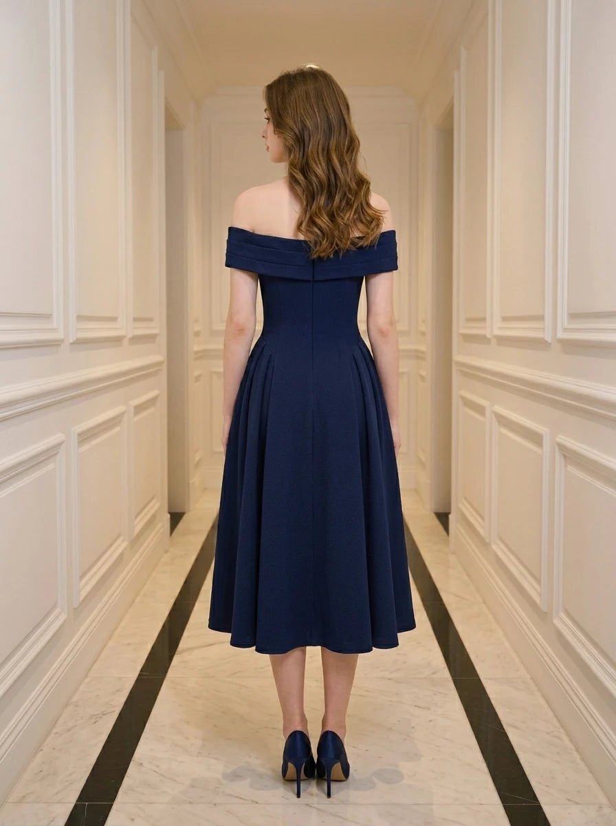 Woman wearing a navy blue off-the-shoulder midi dress with a pleated skirt