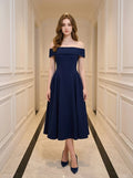 Woman wearing a navy blue off-the-shoulder midi dress with a pleated skirt