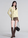 full body shot of a woman wearing a light yellow knit top and brown skirt