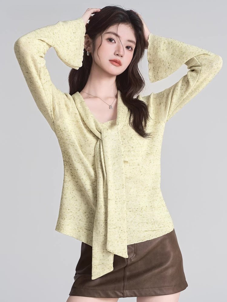 woman wearing a light yellow knit top with tie neck and ruffle detail