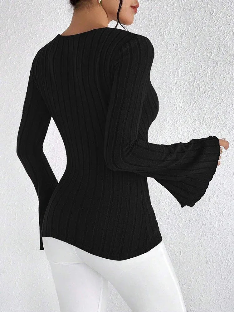 Back view of a woman wearing a black long-sleeved ribbed knit top with flared sleeves