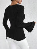 Back view of a woman wearing a black long-sleeved ribbed knit top with flared sleeves
