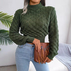 Woman wearing a green cropped mock neck sweater with textured diamond pattern and light wash jeans.