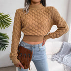 Woman wearing a tan cropped knit sweater with a mock neck and textured pattern.