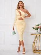 Woman holding a small green handbag while wearing a yellow one-shoulder dress