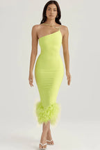Woman wearing a lime green one-shoulder bodycon dress with feather trim hem