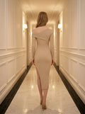 Rear view of a woman in a beige ribbed knit one-shoulder midi dress with a high slit, walking down a hotel hallway.