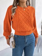 Front view of a woman wearing an orange cropped cable knit sweater.