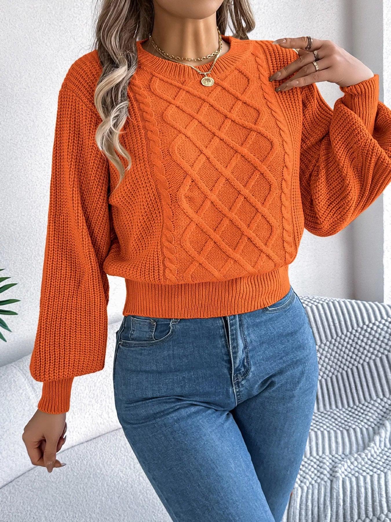 Woman wearing an orange cable knit sweater with balloon sleeves.