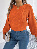 Woman holding a white handbag while wearing an orange knit sweater.