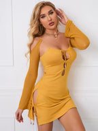 Close-up of a woman in a yellow bodycon dress with cutout details and long sheer sleeves.