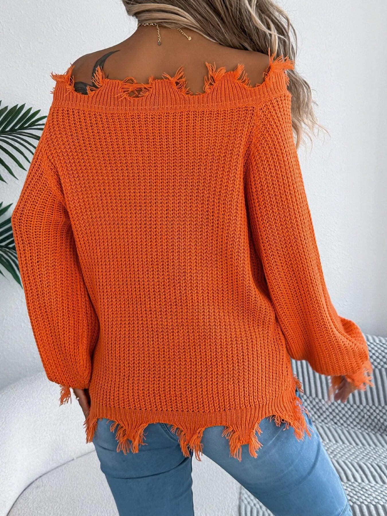 Back view of a woman wearing an orange off-the-shoulder distressed knit sweater