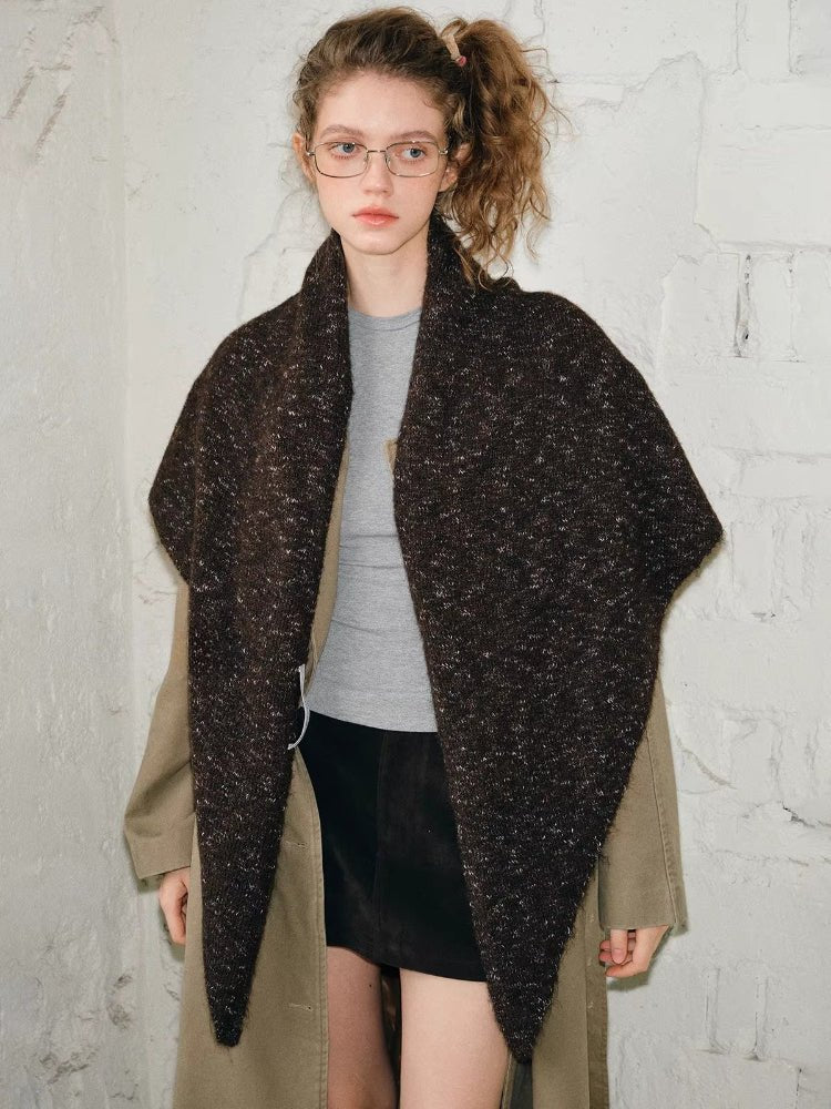 Woman wearing a brown textured knit shawl wrapped around her shoulders over a tan trench coat.