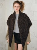 Woman in a tan trench coat with a brown textured knit shawl draped over her shoulders.