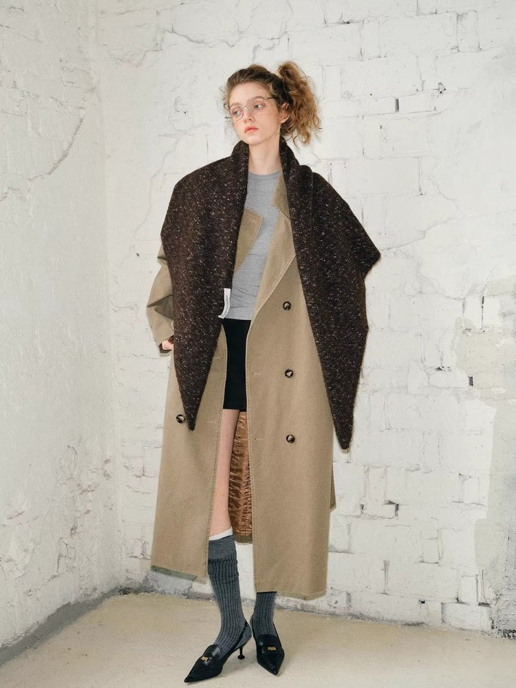 Full body shot of a woman wearing a tan trench coat and a brown textured knit shawl.